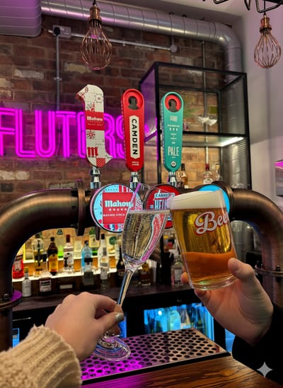 Pints being poured and raised for a cheers at the bar