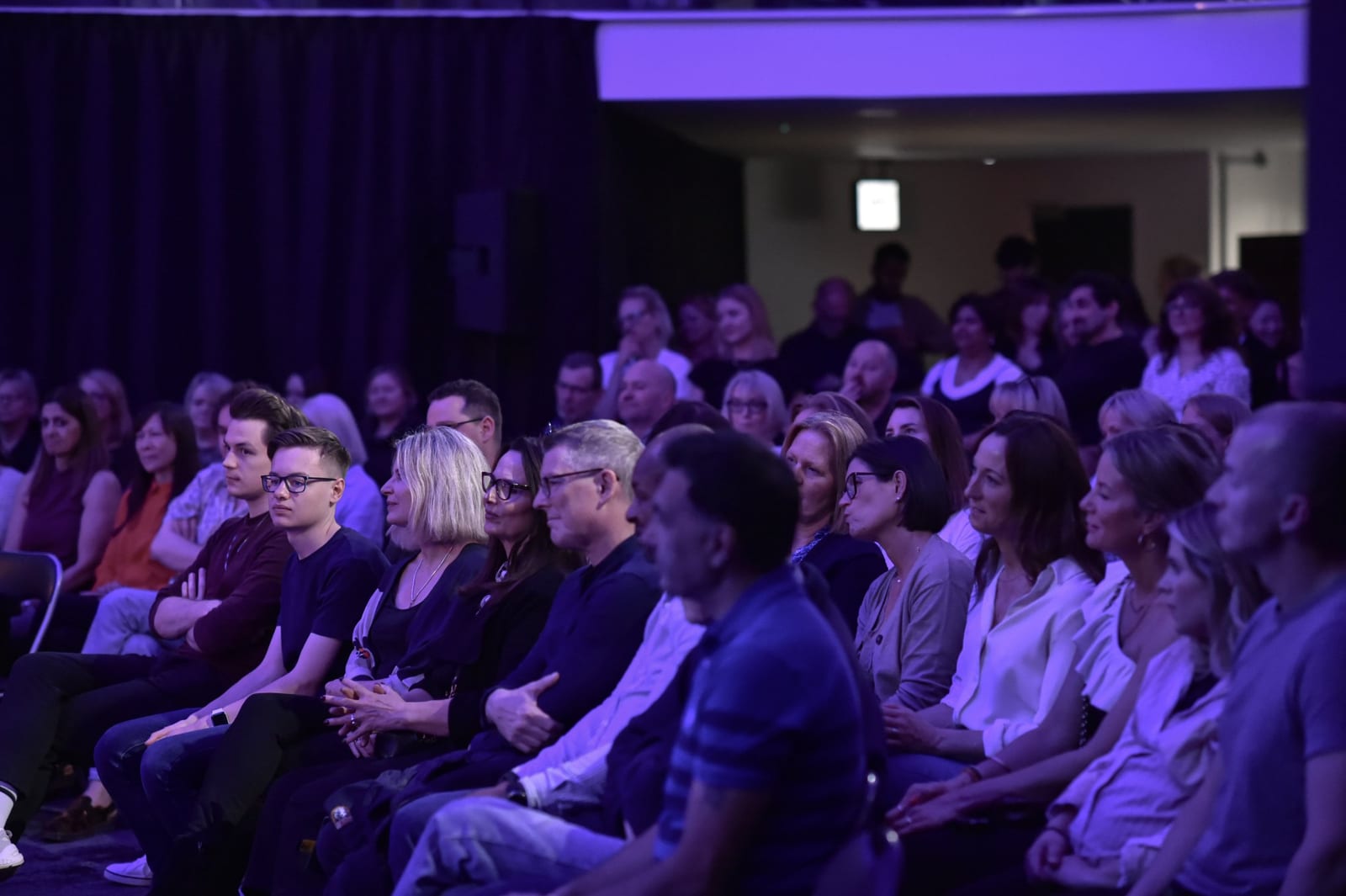 An audience under purple lights at a 1 Mill Street event