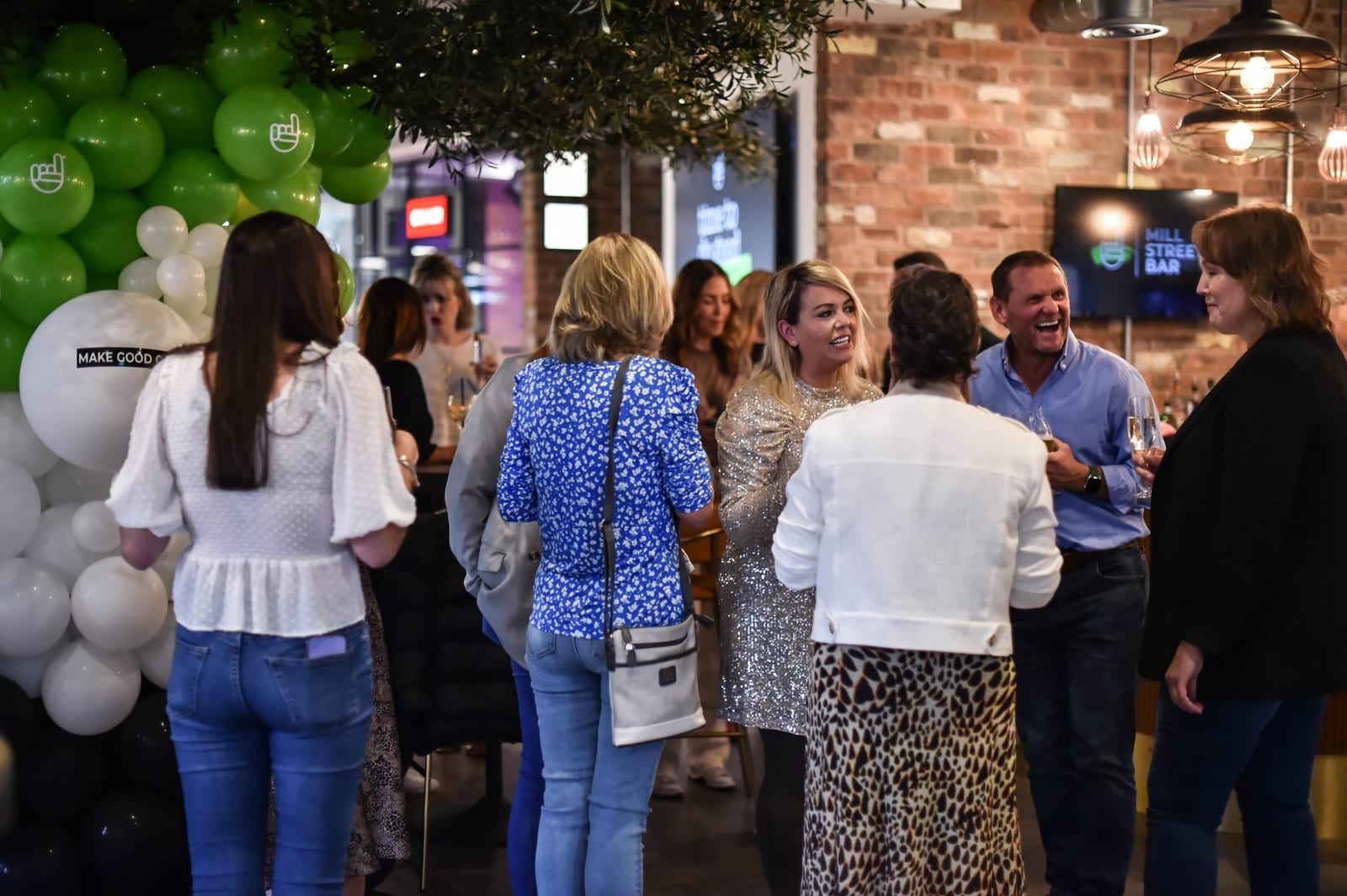Guests networking under balloons at a party at 1 Mill Street