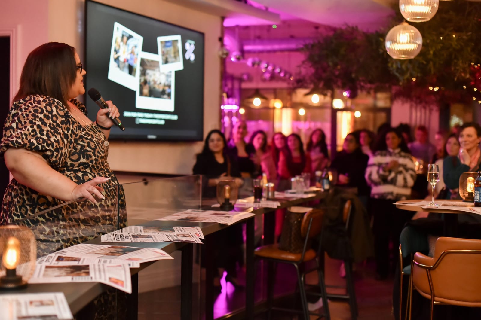 A speaker on stage under pink lights