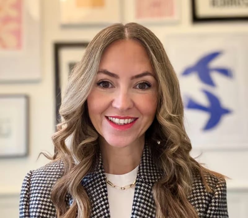 Georgina Waterhouse of The W Agency smiling in a houndstooth blazer in front of framed prints