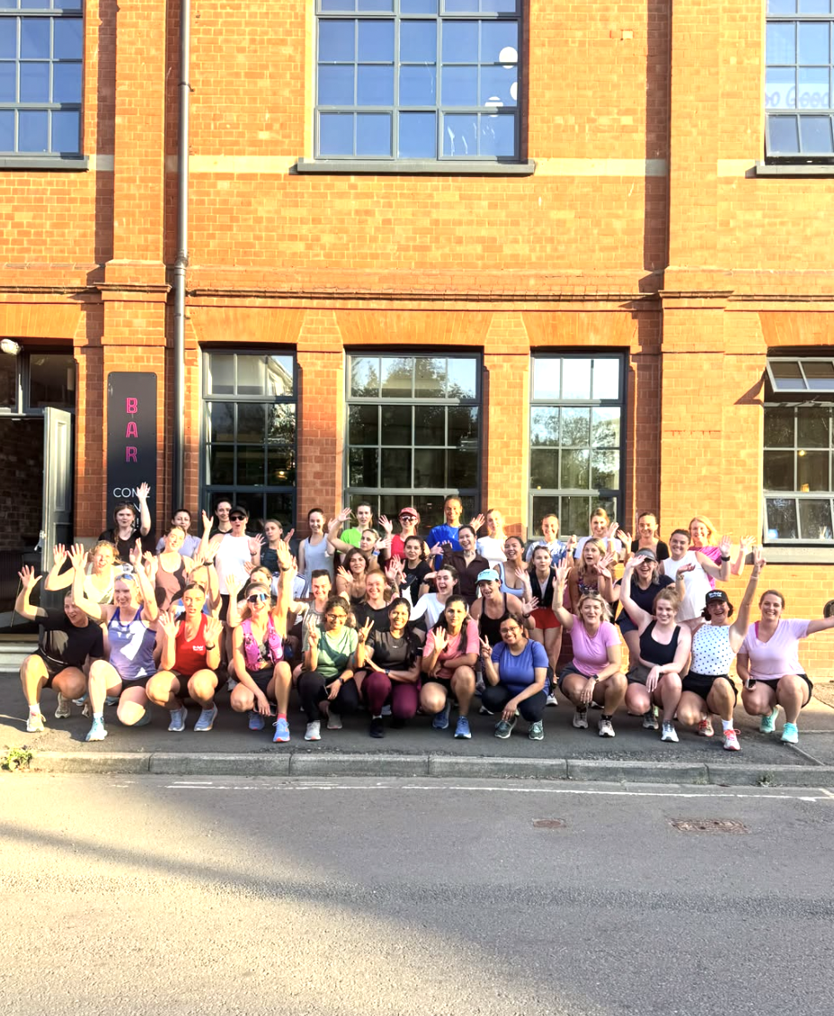 A group of women in running clothing grouped for a photo at the side of the road